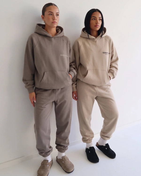 Zwei Models in Essentials Hoodie-Sets vor weisser Wand